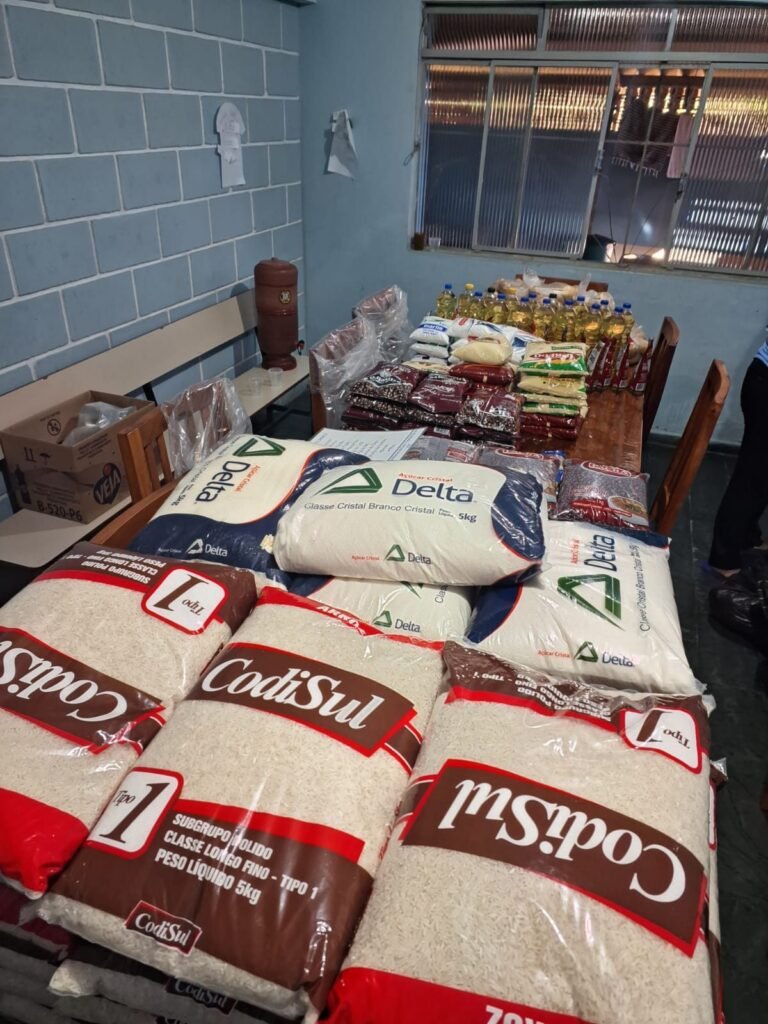 Mesa do CEEB coberta de sacos de arroz e feijão e garrafas de óleo reunidos em uma campanha de arrecadação de alimentos.